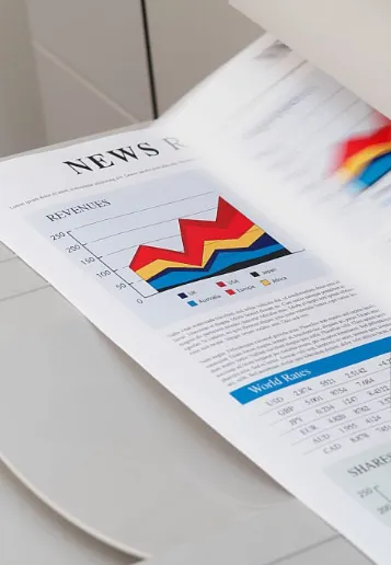 Printed documents with charts and graphics coming off a copier