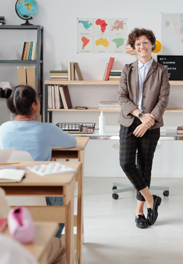 Teacher standing in a classroom while learners work at their desks