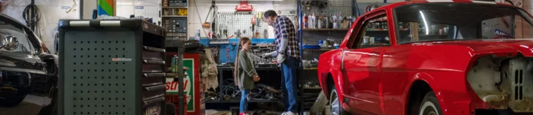 Mechanic working on a red classic car in an auto repair workshop