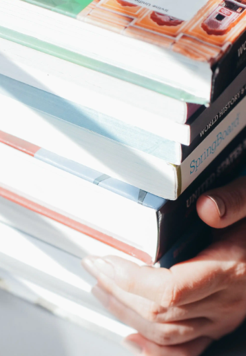 Hands holding a stack of printed and bound books